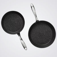 Two Westinghouse black frying pans with speckled texture on a light grey background
