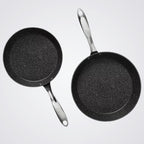 Two Westinghouse black frying pans with speckled texture on a light grey background