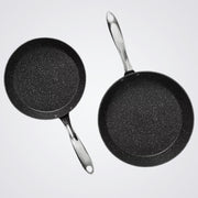 Two Westinghouse black frying pans with speckled texture on a light grey background