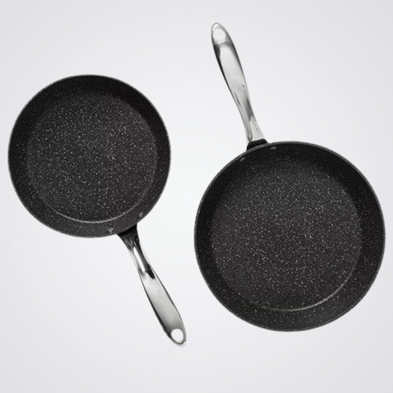 Two Westinghouse black frying pans with speckled texture on a light grey background