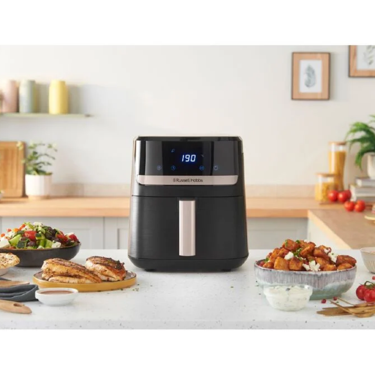 Black air fryer on a kitchen counter with various dishes around it.