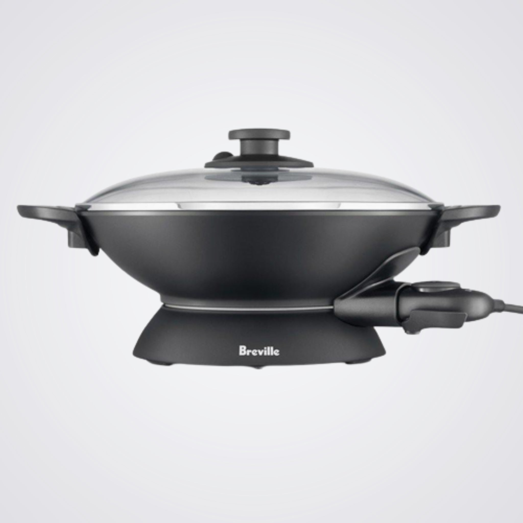 Black electric wok with glass lid on a light background, featuring the Breville brand.