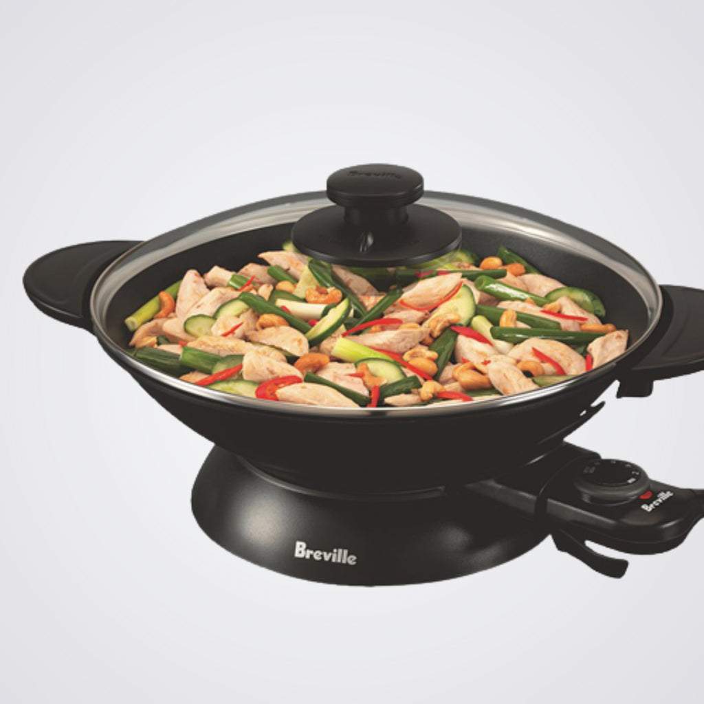 Breville electric wok with food inside on a light background