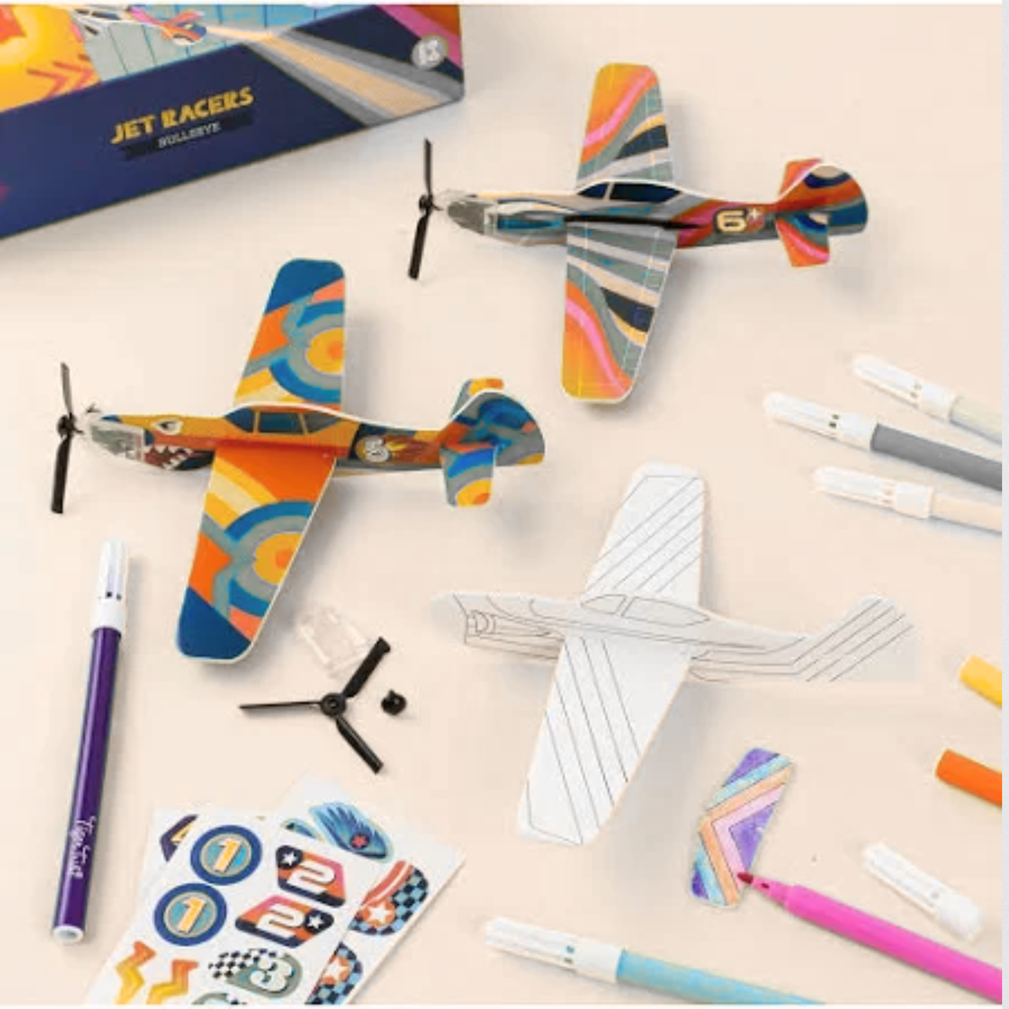Colorful toy airplanes on a table with markers and stickers.